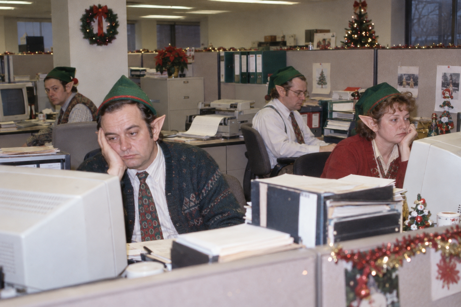 Elf office staff at their beige cubicles and CRT computers.